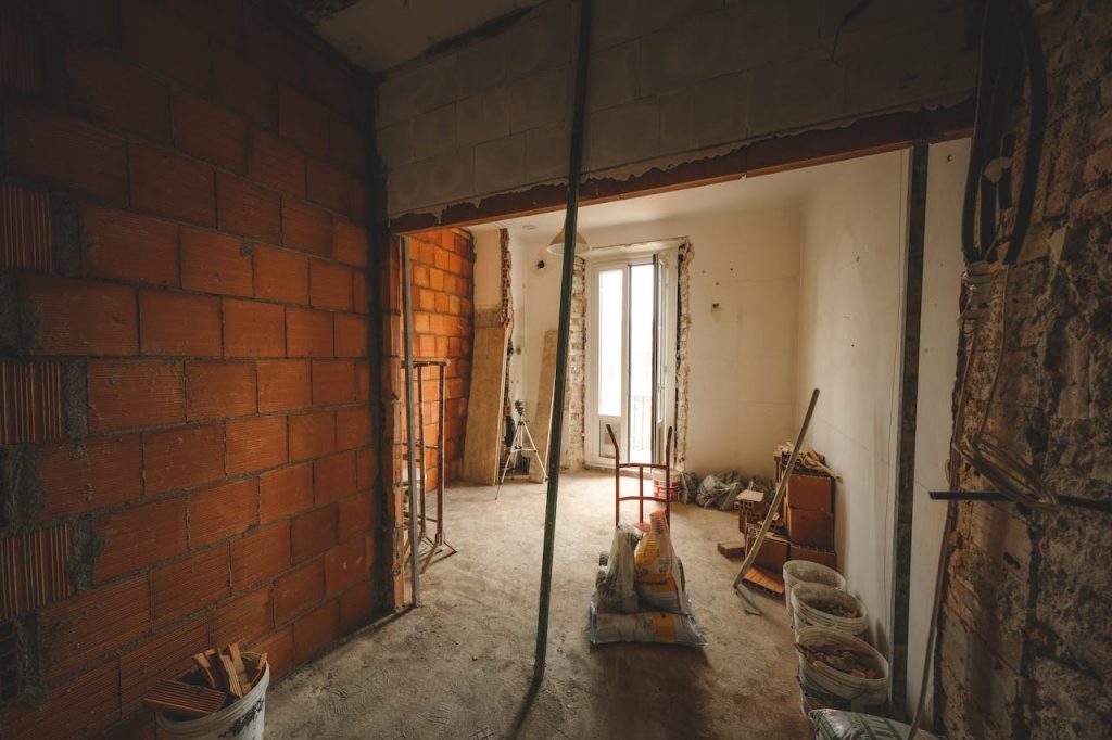 major-home-renovation-15798781 A partially renovated room with exposed brick walls and construction materials on site.