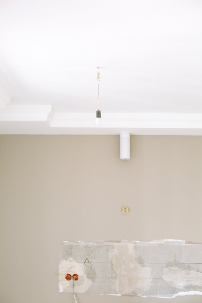 A minimalistic room undergoing renovation featuring exposed light fixture and wall sockets.