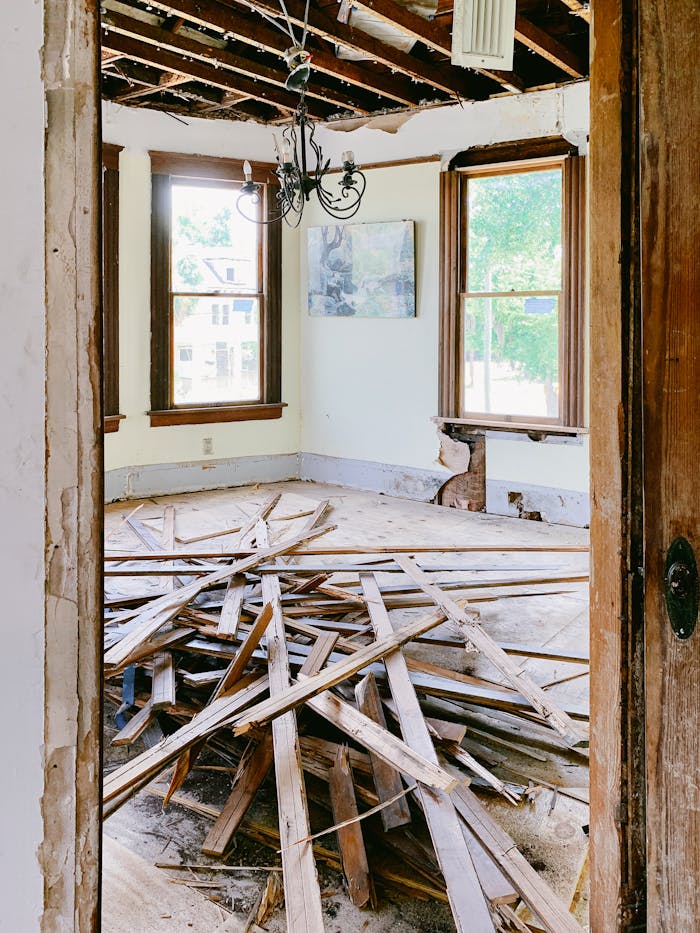 wooden-planks-on-the-floor-in-a-house-during-demolition-4756488 Interior room under renovation with exposed beams and planks piled on the floor.
